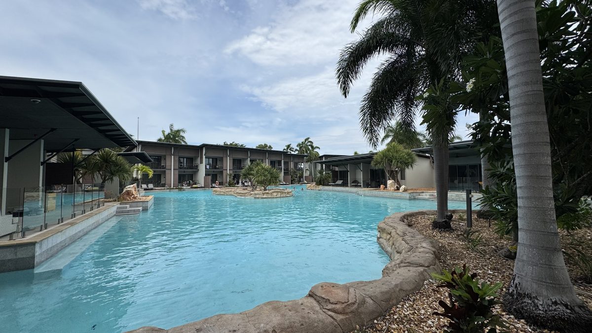 Swim-out resort pool framed by palms and lodge buildings